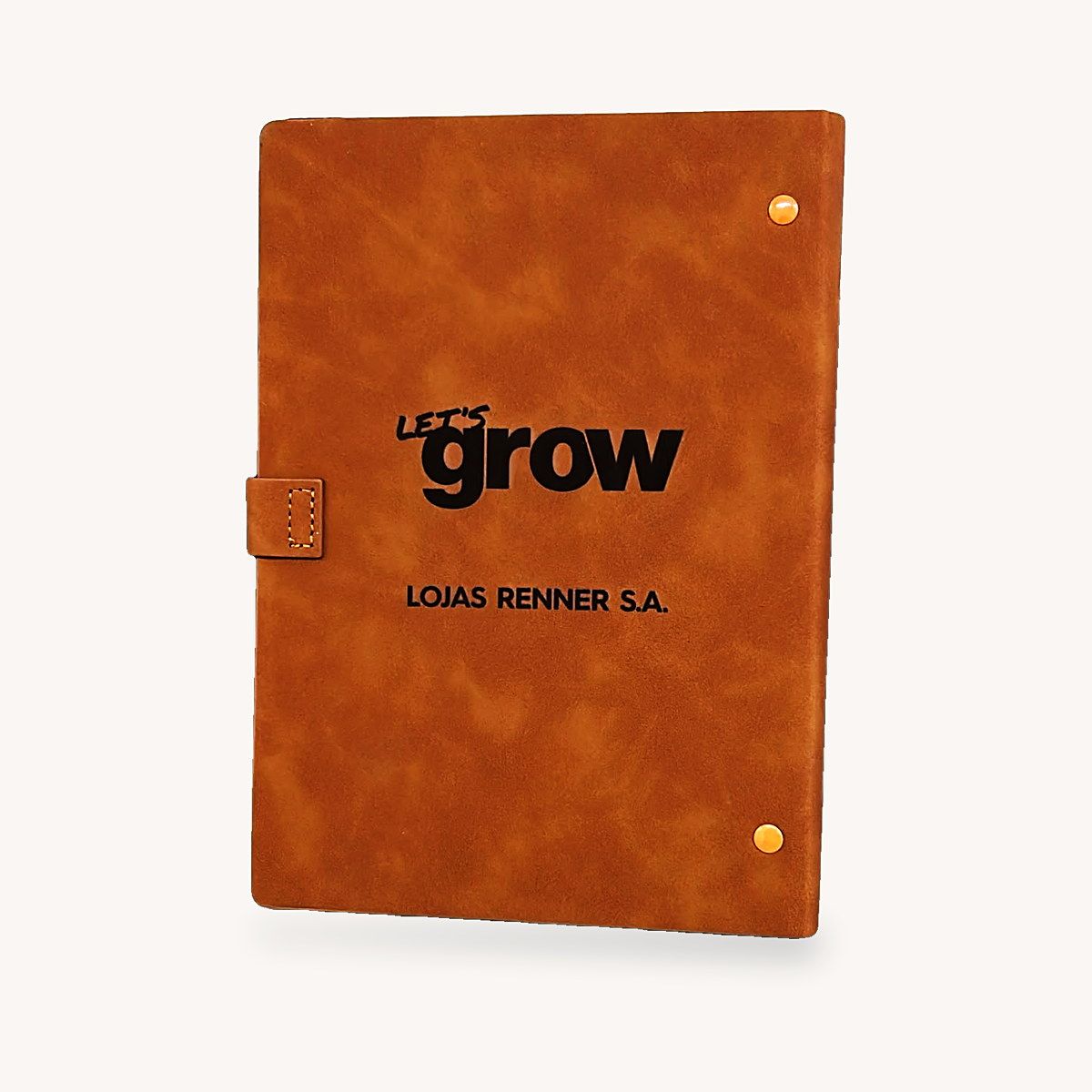 Caderno de couro caramelo com a marca Let's Grow e o nome Lojas Renner S.A. gravados a laser