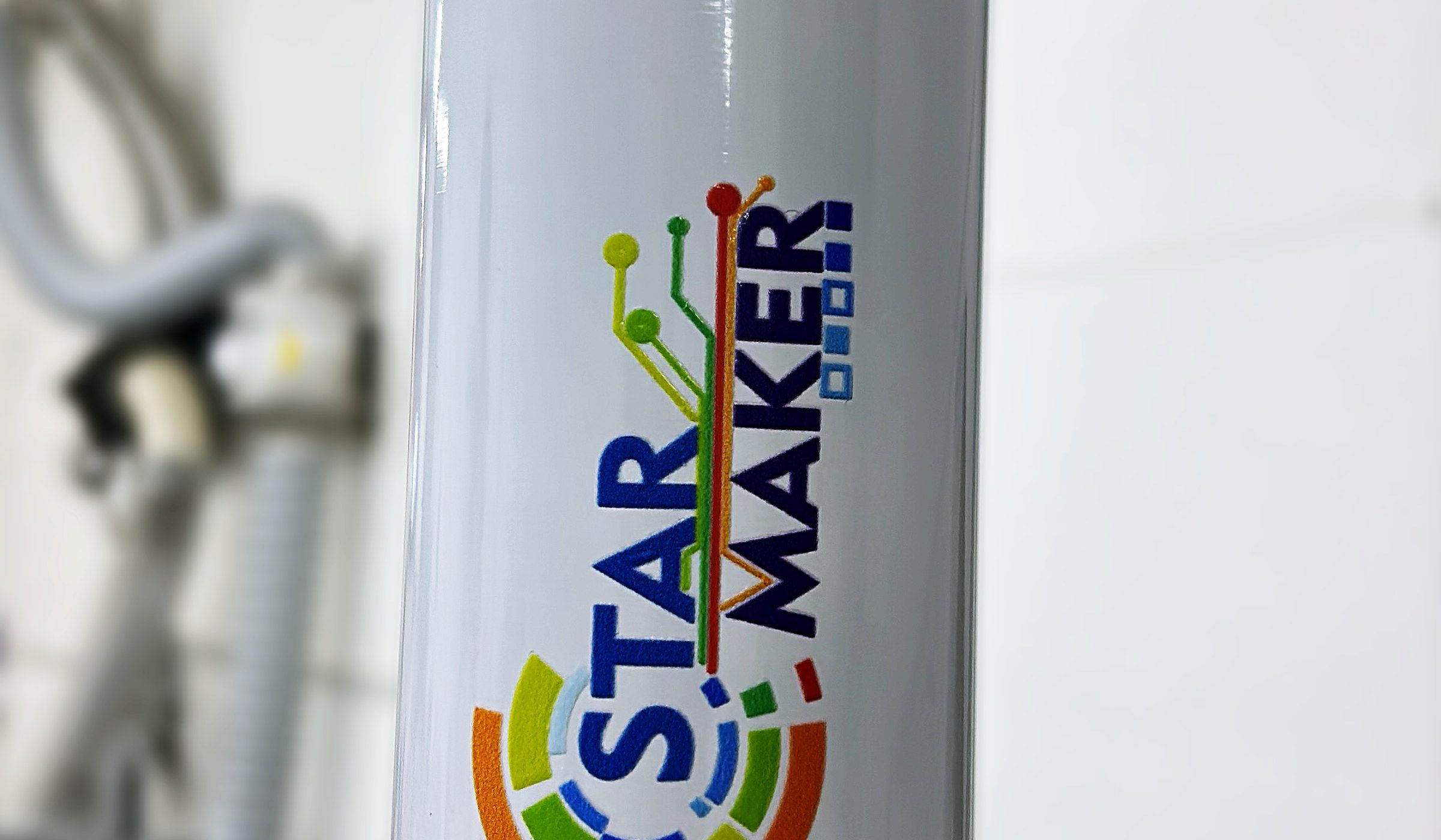 Garrafa térmica branca com o adesivo colorido Star Maker aplicado, sobre a mesa da máquina
