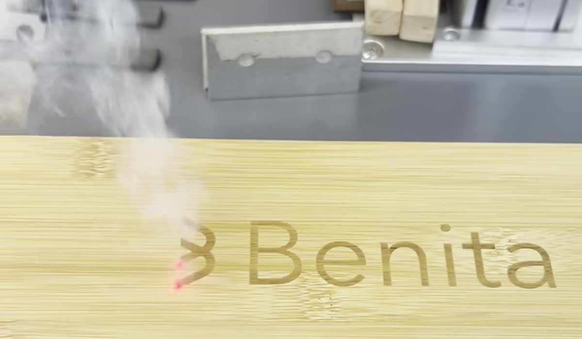 Caixa de bambu sendo gravada a laser, com fumaça subindo da superfície